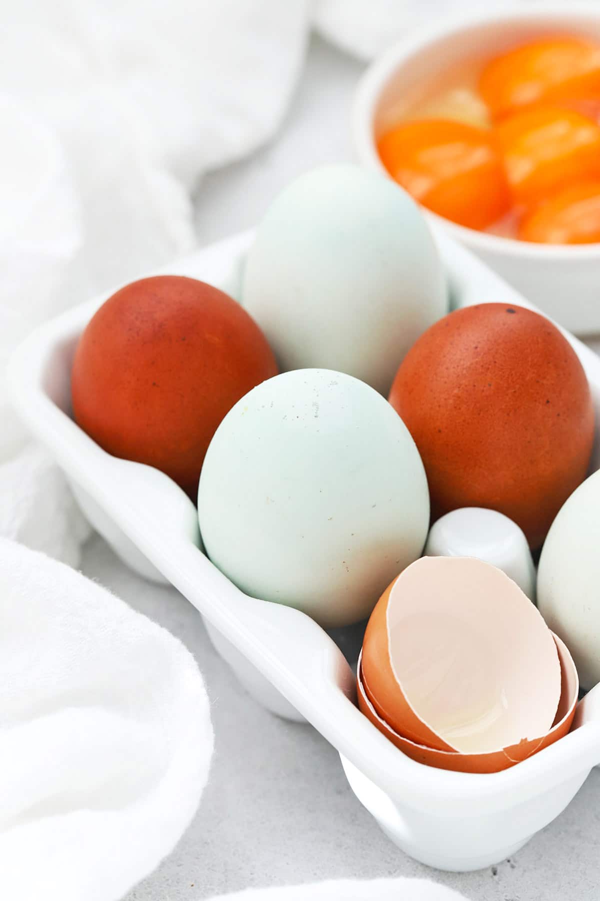Front view of colorful farm eggs in a white egg carton