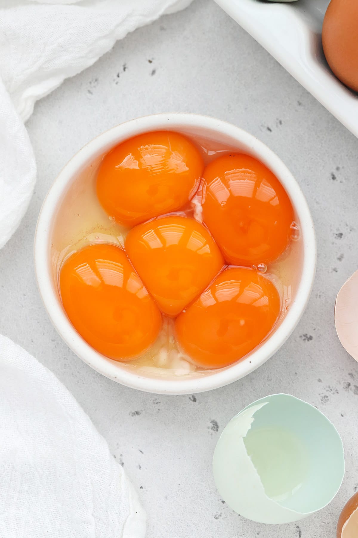 Overhead view of egg yolks in a small white bowl