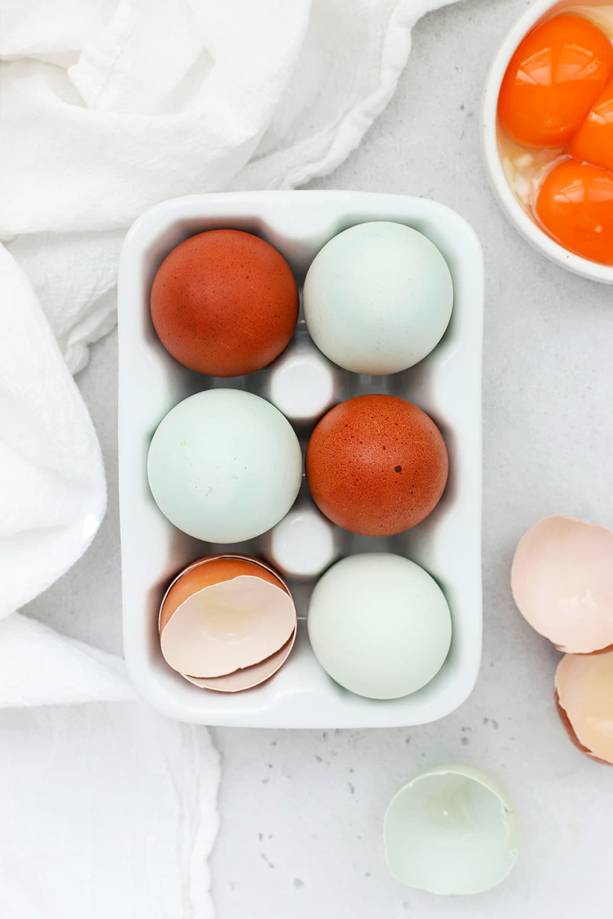 Overhead view of colorful farm eggs in a white egg carton