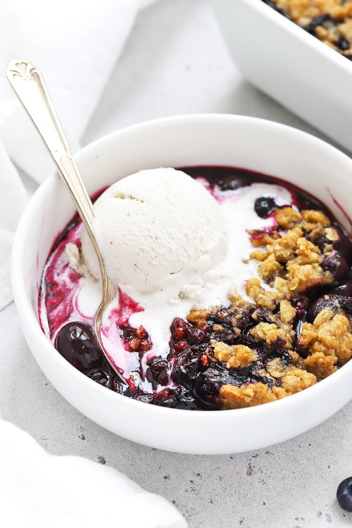 Front view of gluten-free blueberry crisp topped with vanilla ice cream