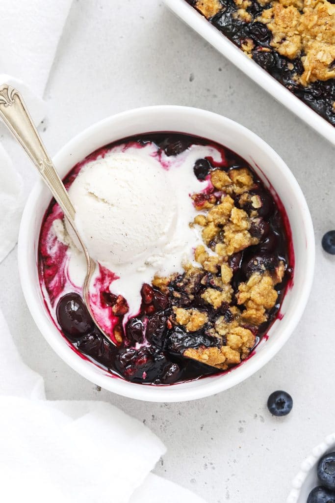 Overhead view of gluten-free blueberry crisp topped with melting vanilla ice cream
