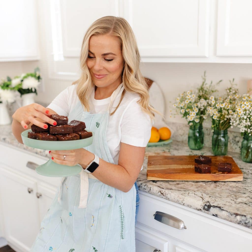 Emily Dixon from Sweets And Thank You stacking gluten-free brownies on a green cake stand