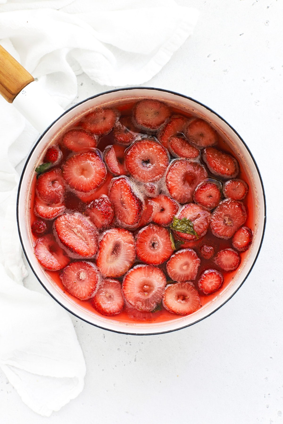 Simmering strawberry basil simple syrup to make strawberry basil lemonade