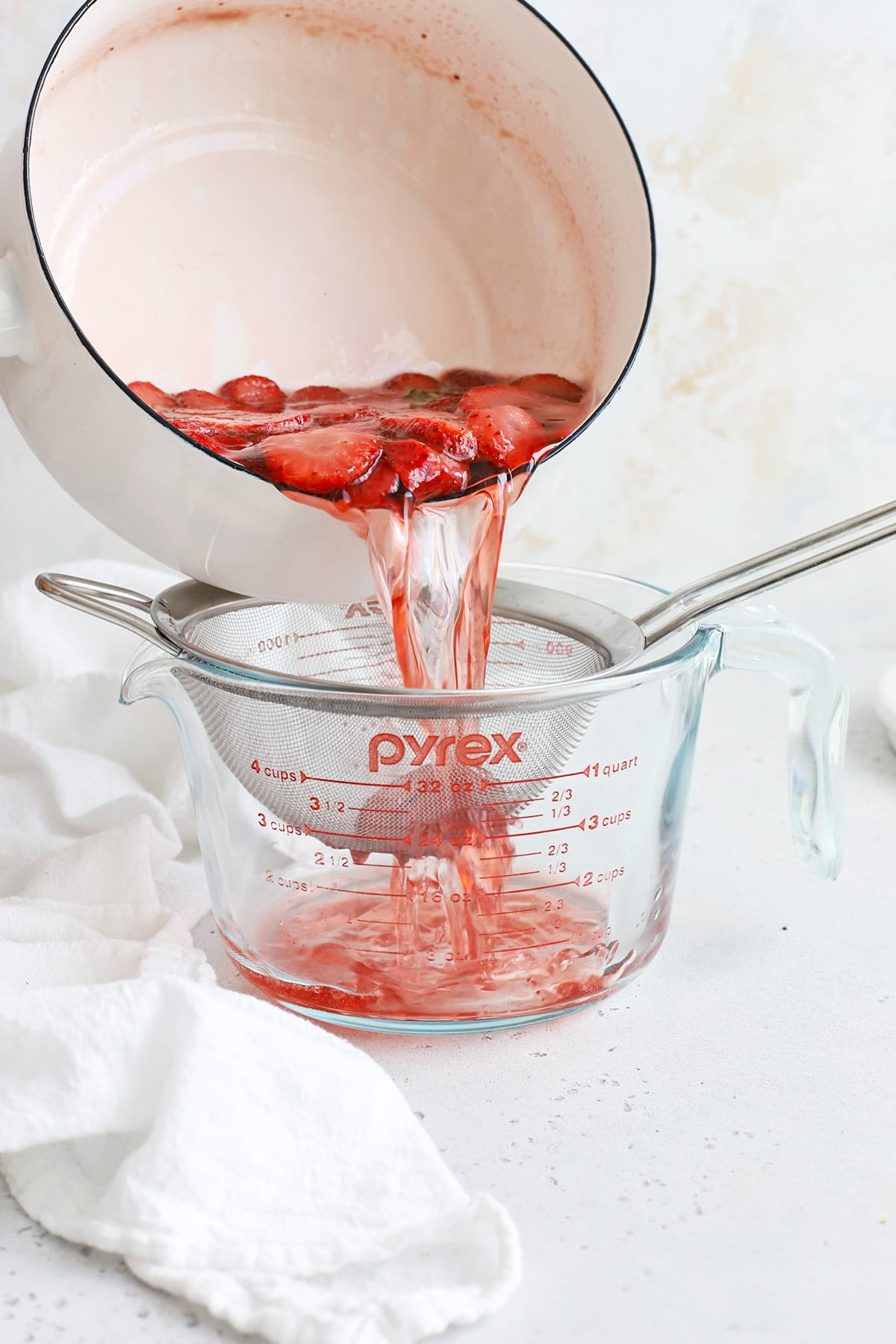 Straining strawberry basil simple syrup