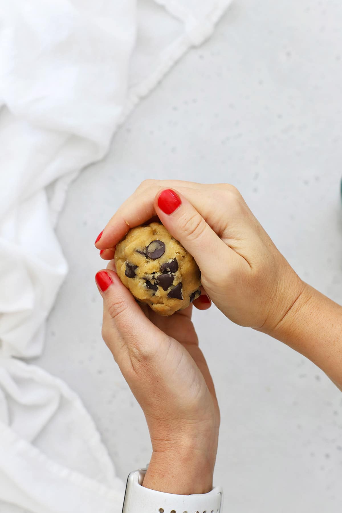 Rolling out balls of gluten-free nutella stuffed chocolate chip cookie dough