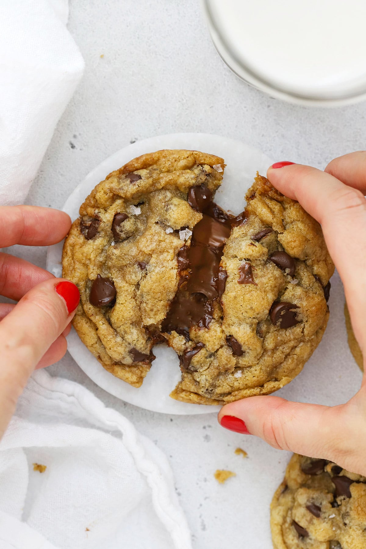 Pulling apart a gluten-free Nutella chocolate chip cookie, revealing the gooey nutella center