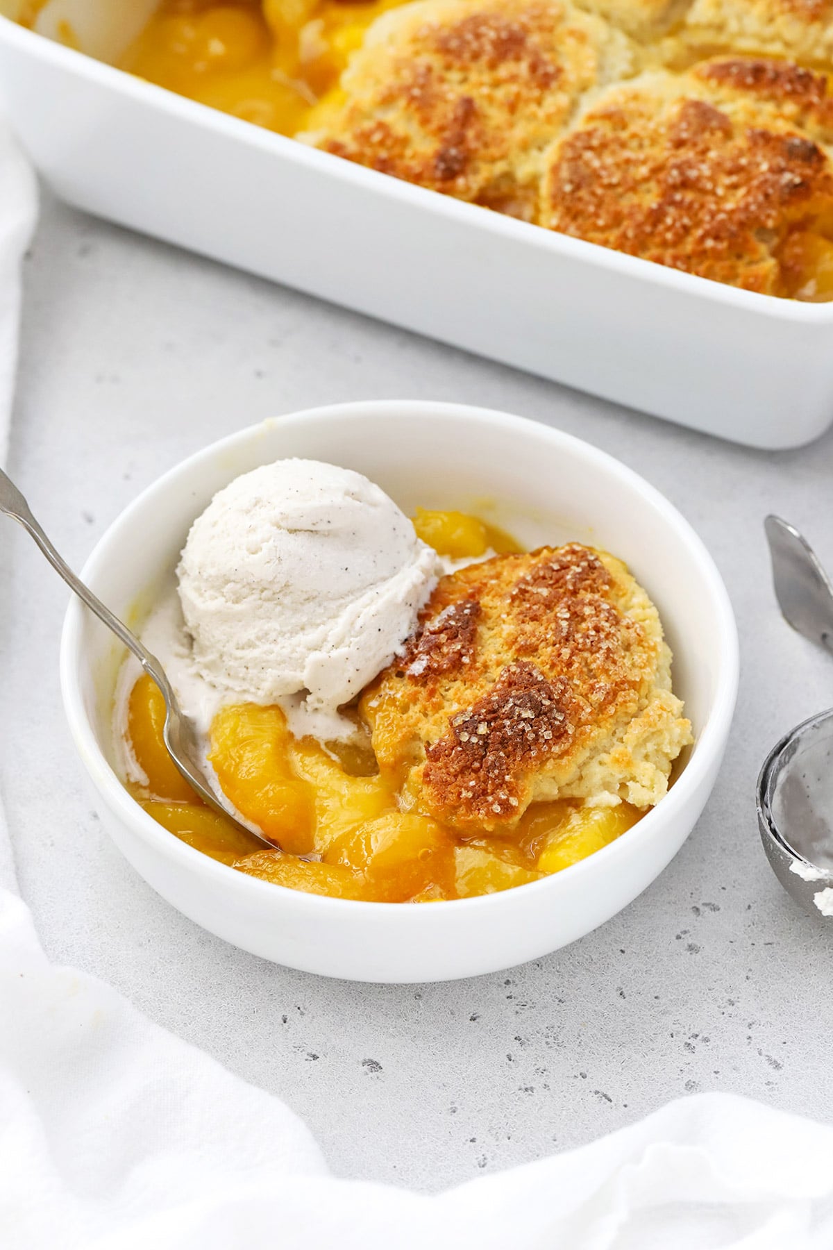 Gluten-free peach cobbler in a bowl topped with vanilla ice cream