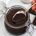 Dipping a spoon into a jar of homemade chocolate syrup