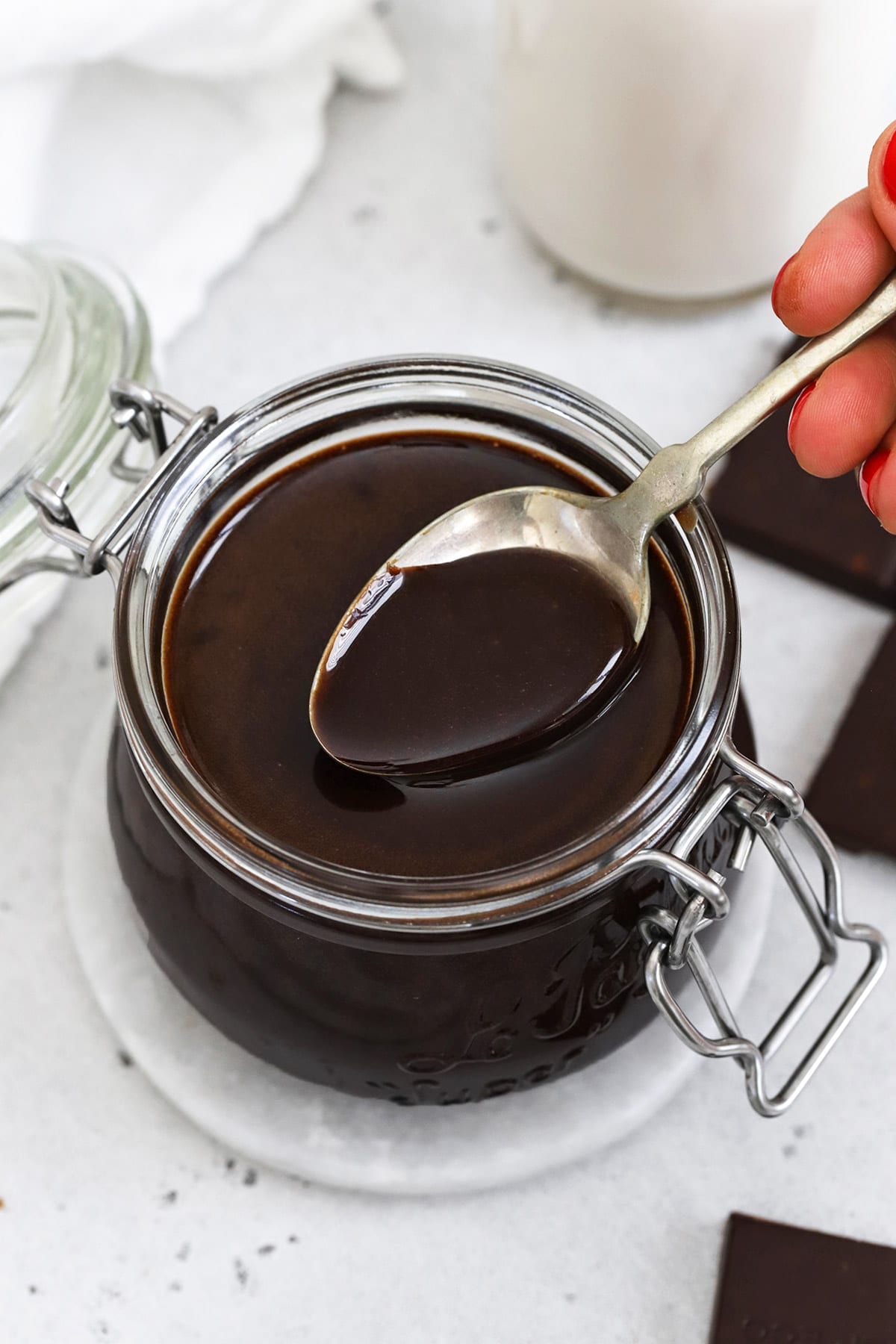 Dipping a spoon into a jar of homemade chocolate syrup