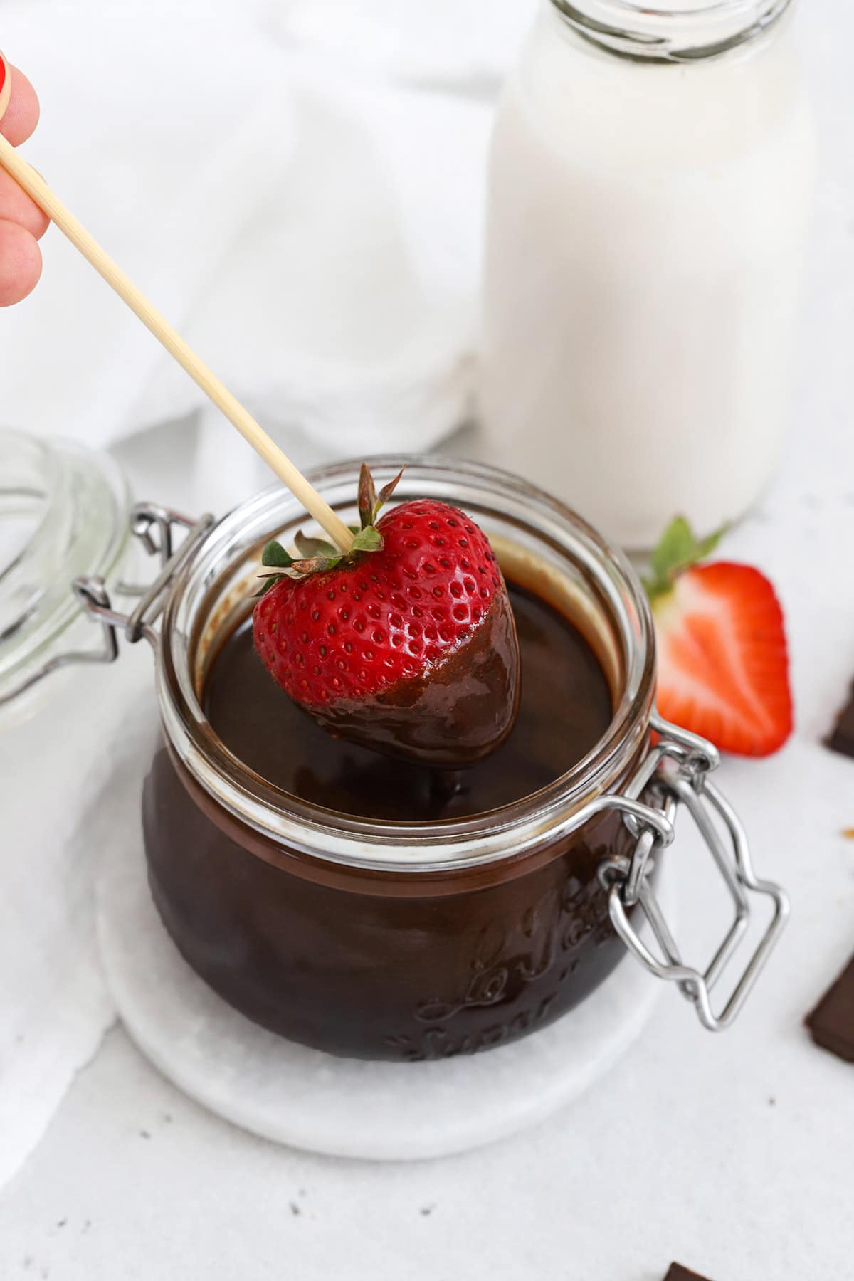 Dipping strawberries into a jar of homemade chocolate syrup