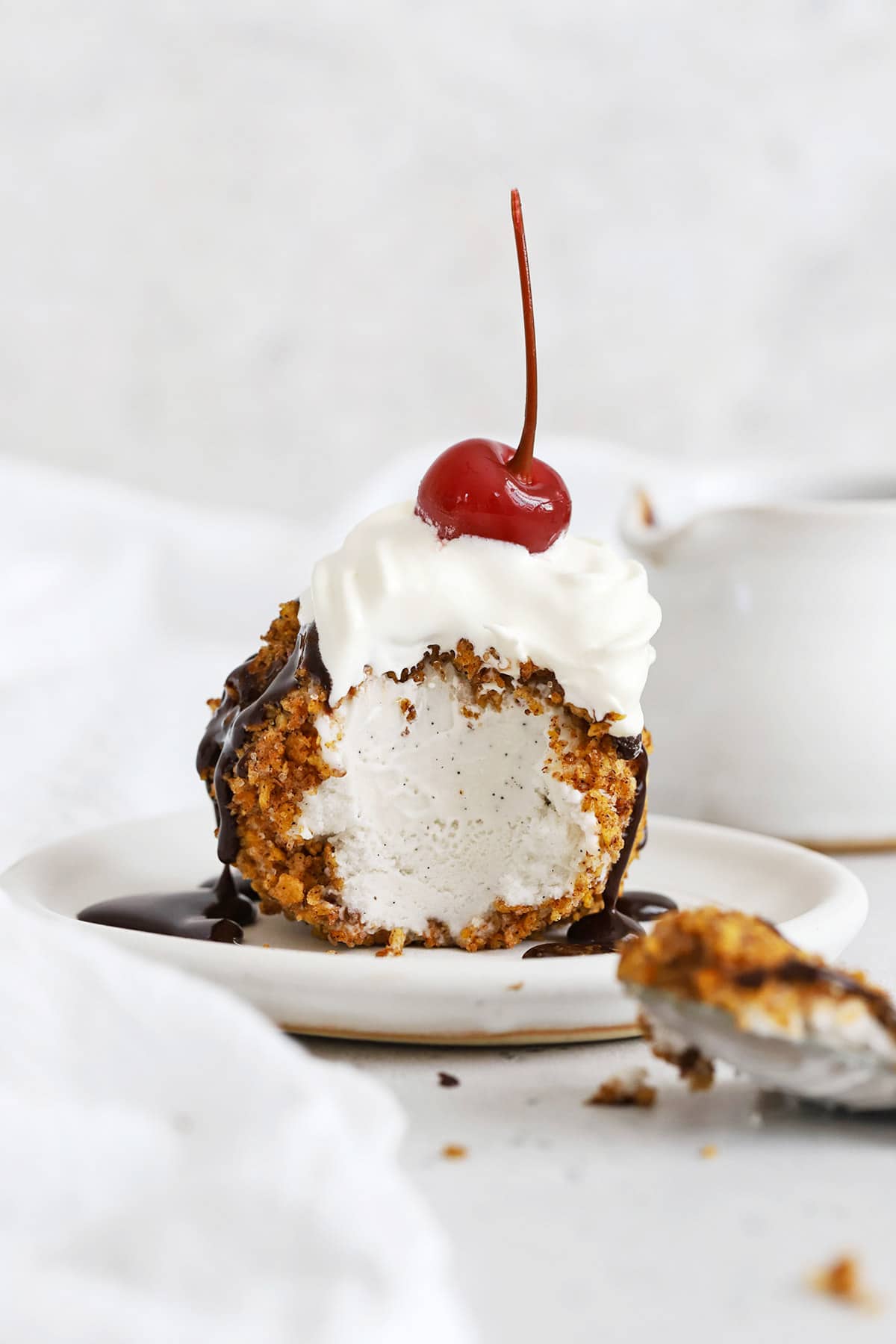 Front view of gluten-free fried ice cream with one bite scooped out of it