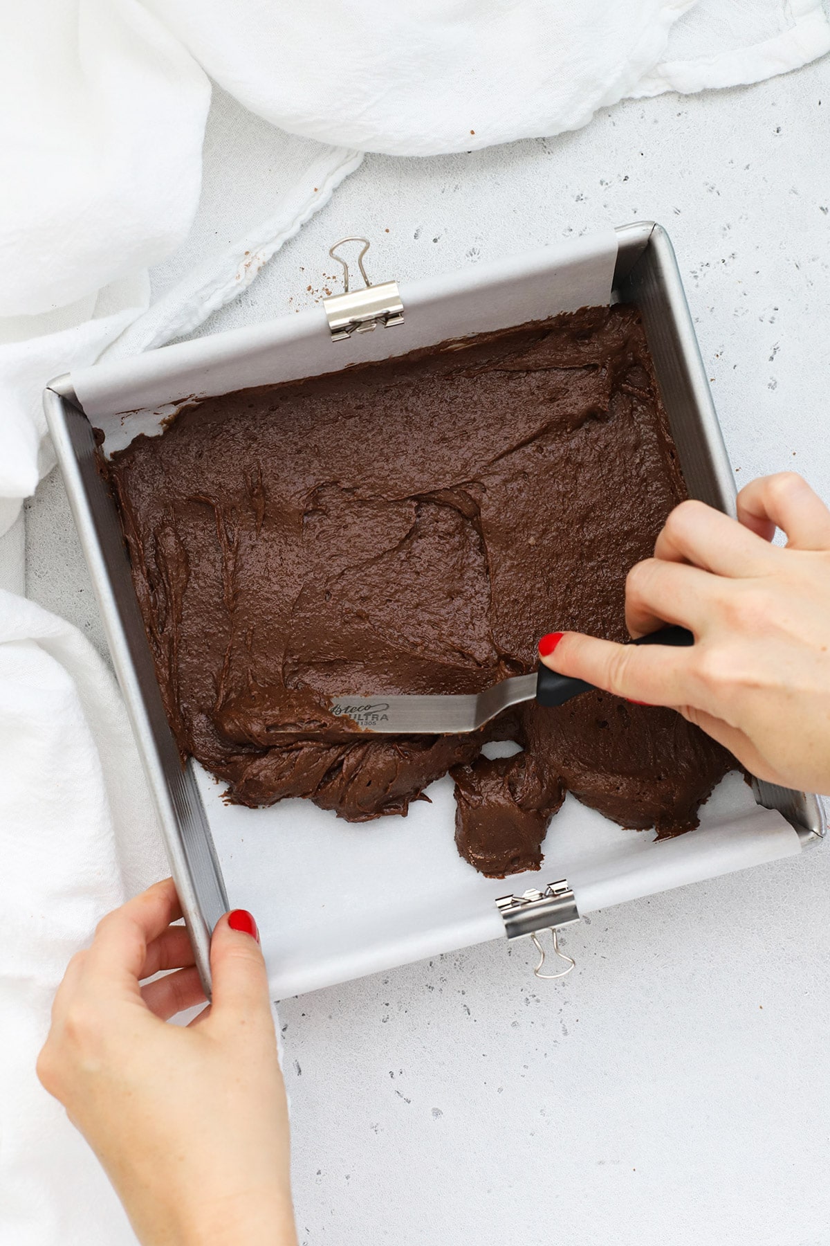 Spreading brownie batter into an 8x8 metal pan to make gluten-free ice cream sandwiches
