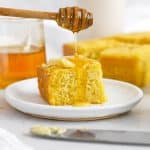 Gluten-free cornbread being drizzled with honey