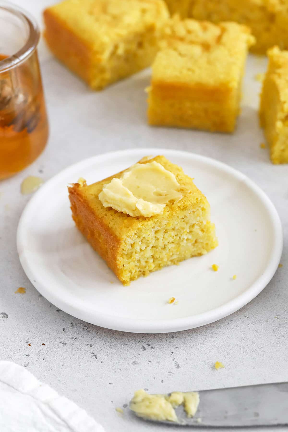 Front view of a slice of easy gluten-free cornbread topped with honey butter