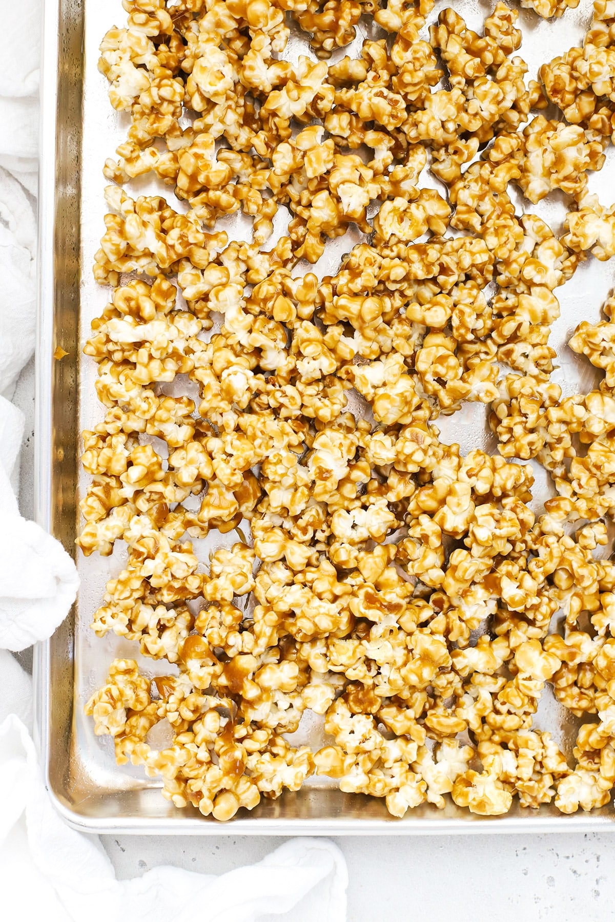 Overhead view of a sheet pan of caramel popcorn before it goes into the oven