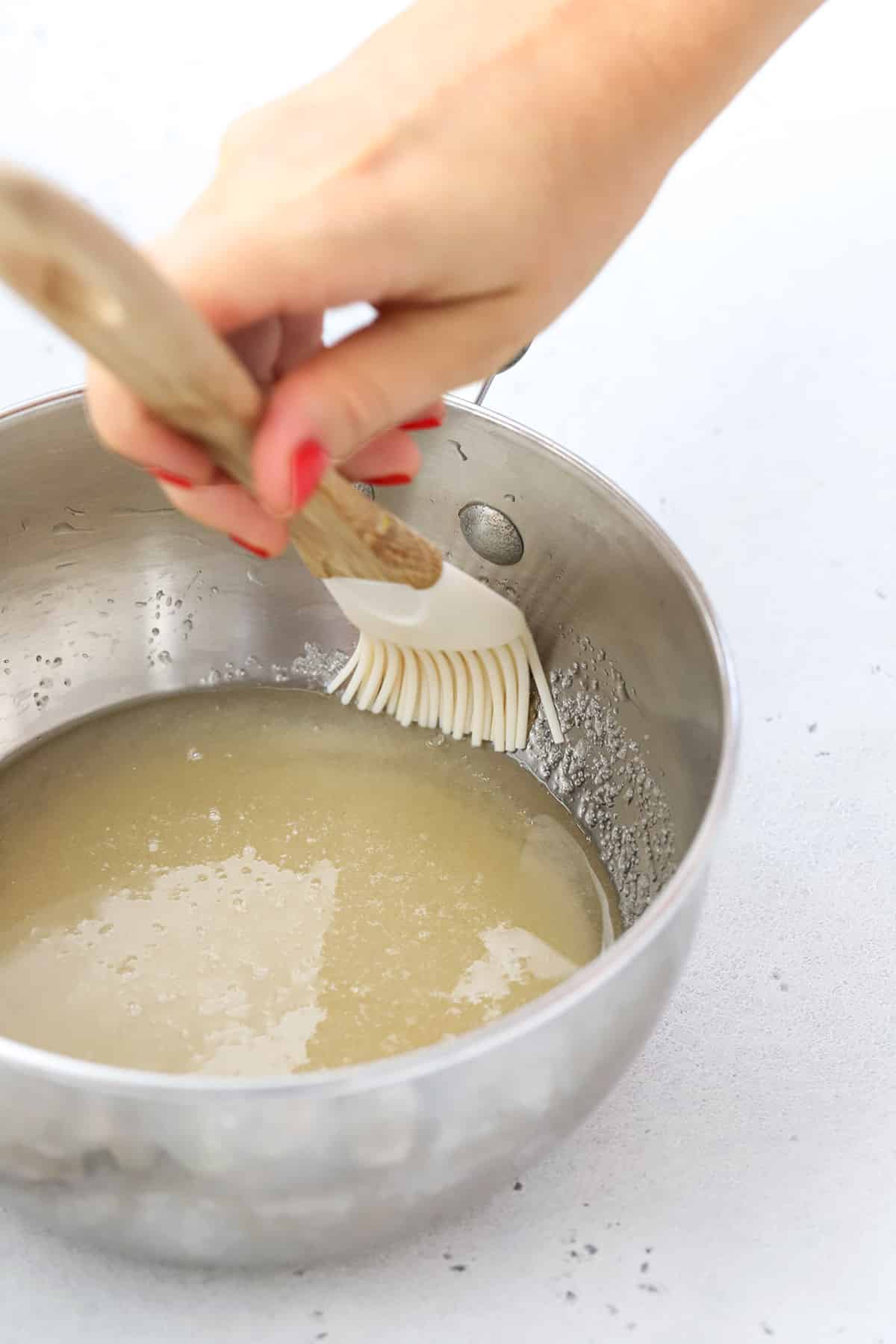 Cleaning sugar crystals off the side of a pan with a pastry brush