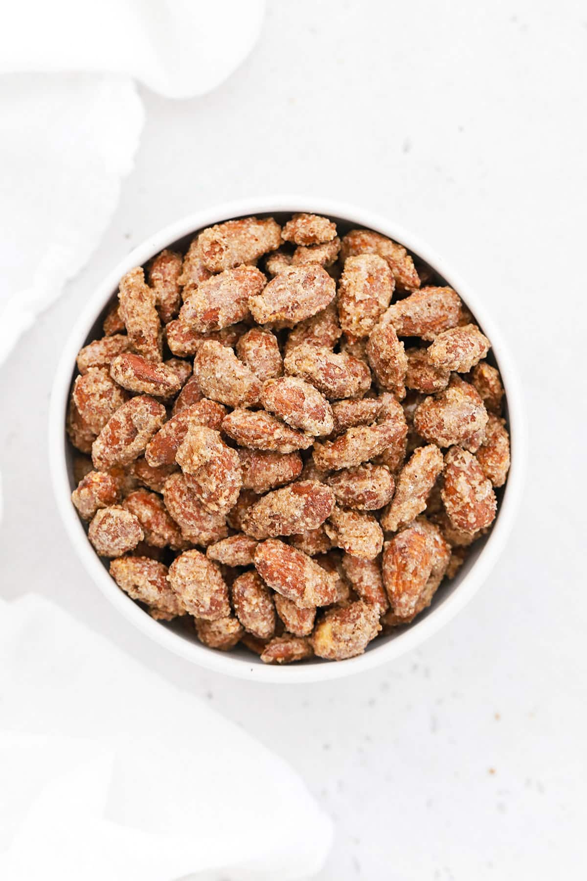 Overhead view of cinnamon almonds in a white bowl