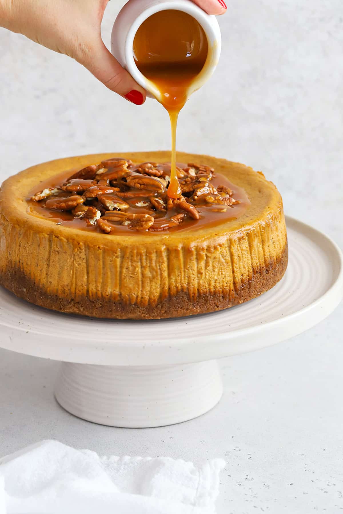 front view of gluten-free pumpkin cheesecake with pecans and caramel sauce
