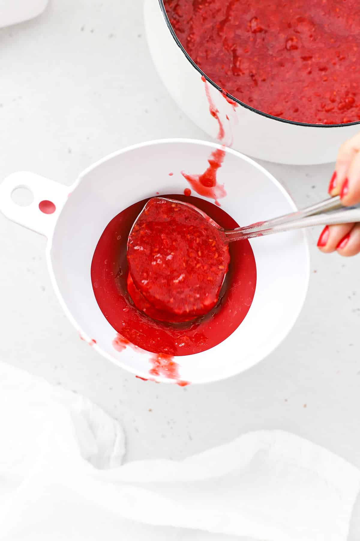 Spooning raspberry freezer jam into jars
