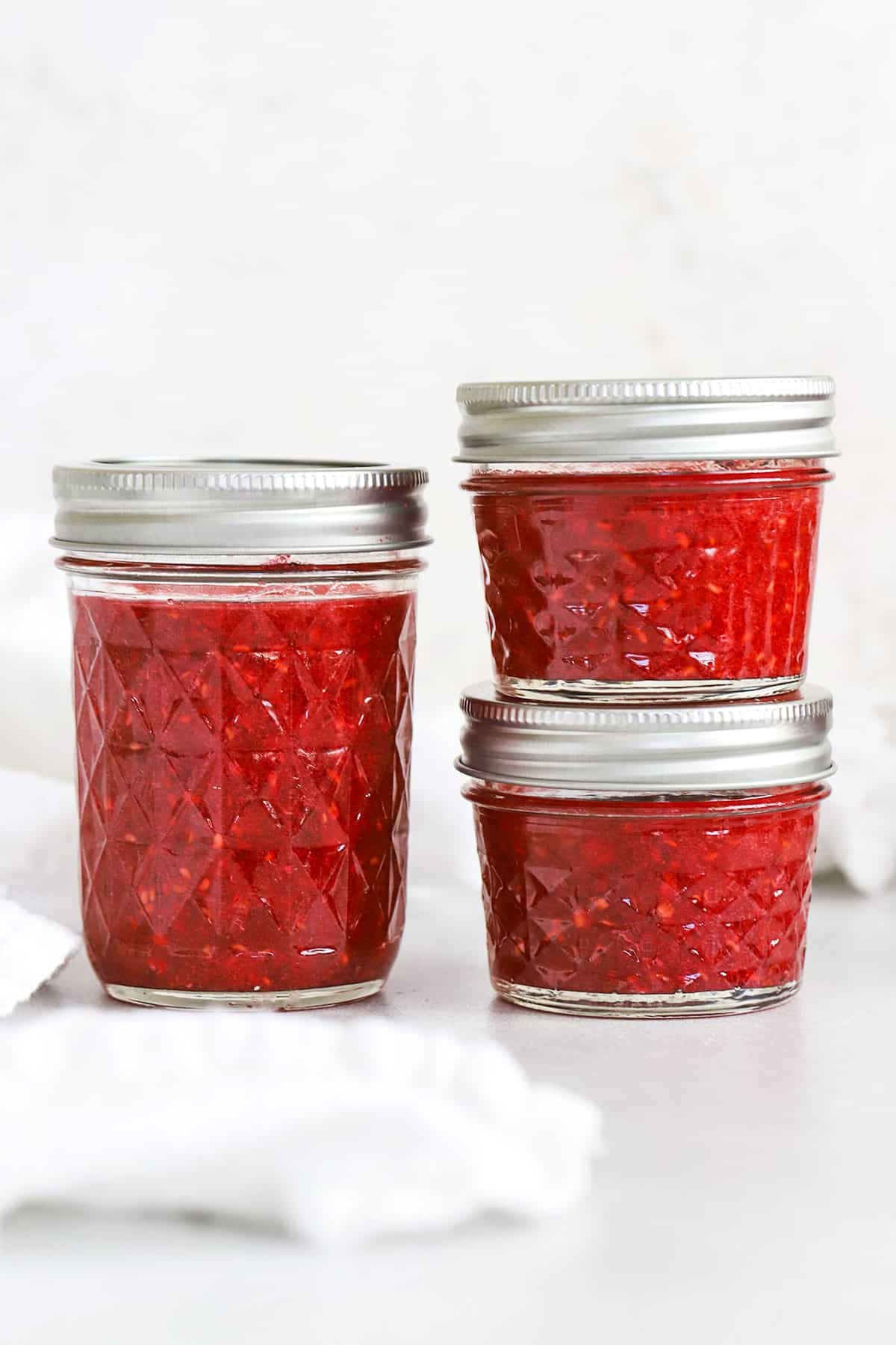 Front view of different sizes of jars of raspberry freezer jam