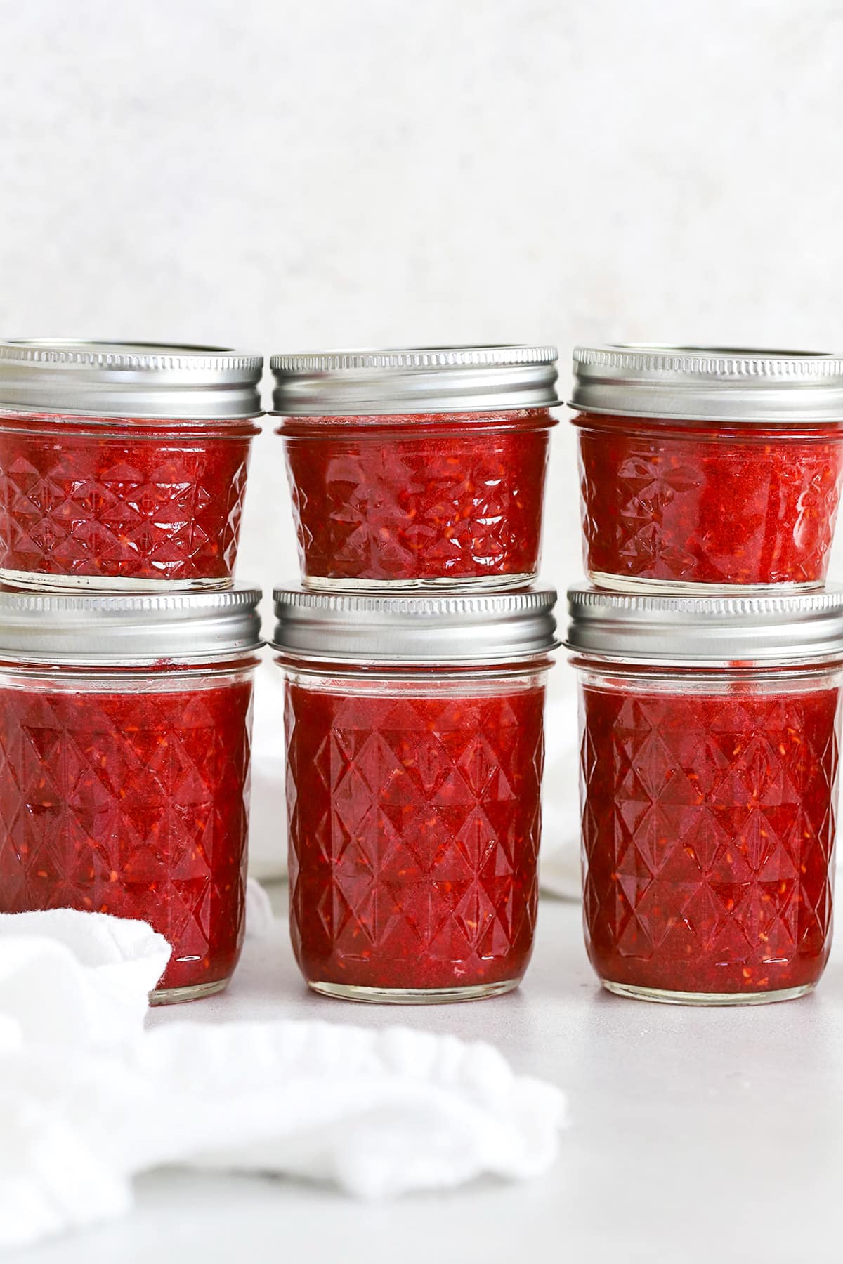 Front view of jars of low sugar raspberry freezer jam stacked