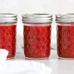 Front view of three jars of easy raspberry freezer jam