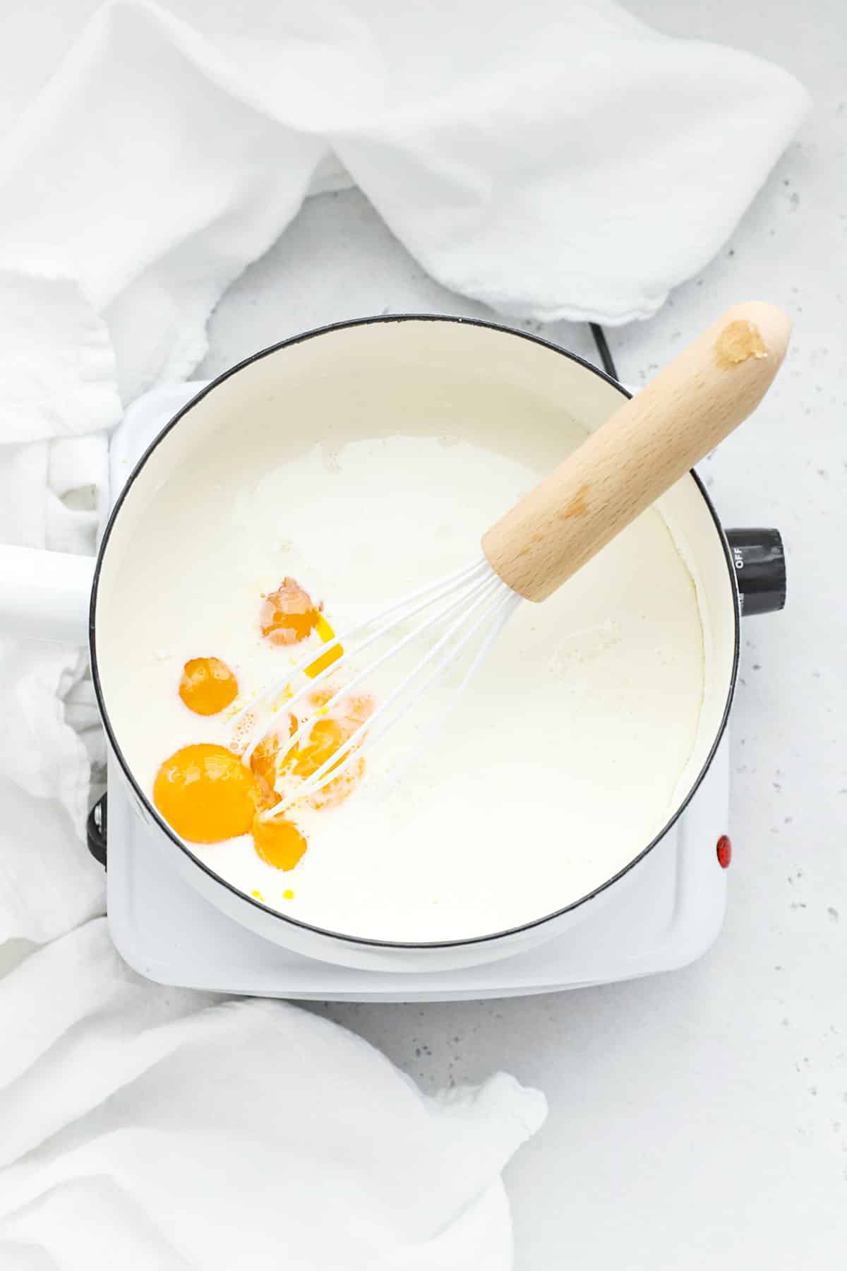 Adding milk, egg yolks, and cream to cornstarch, sugar, and salt to make banana pudding