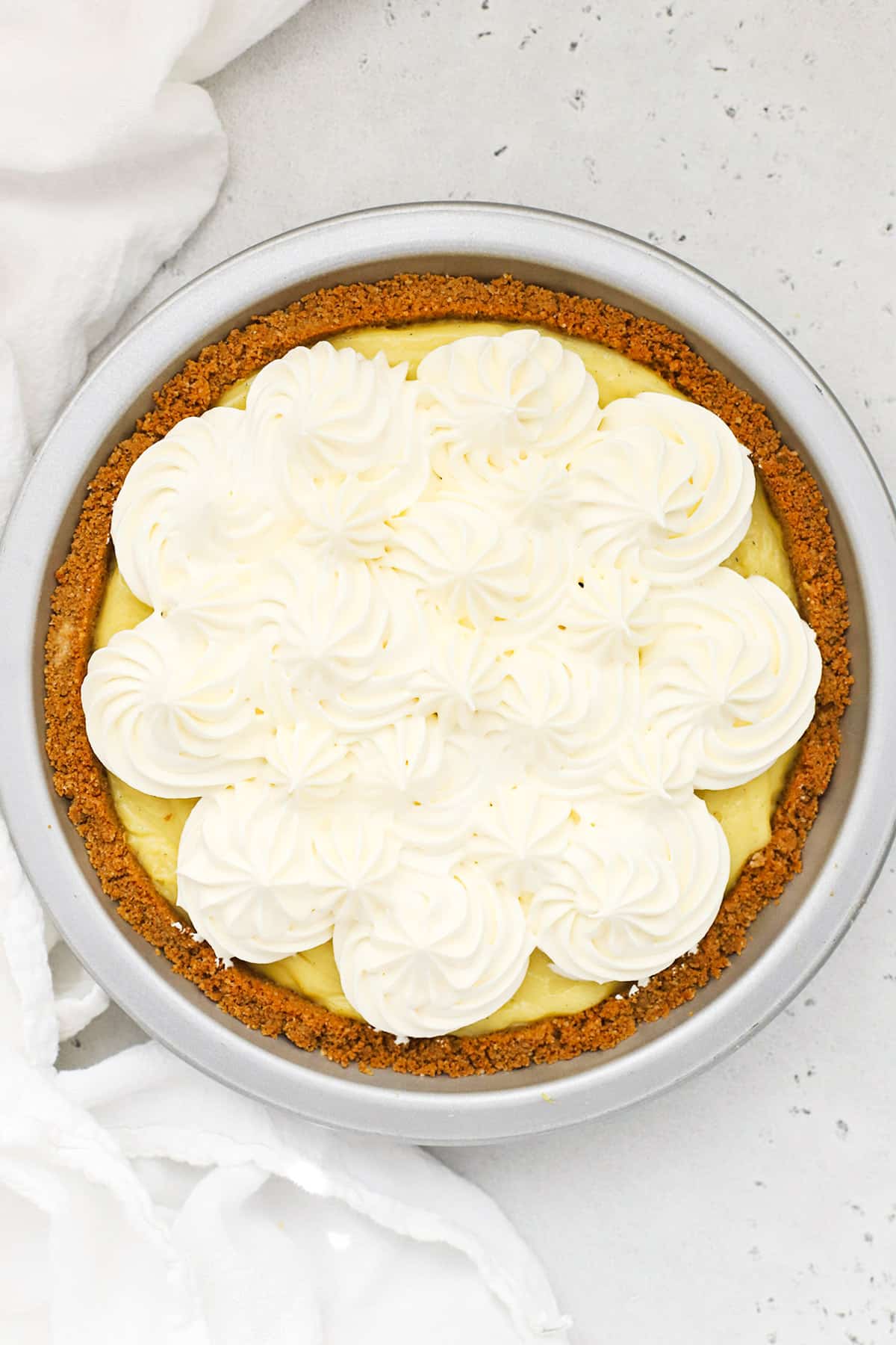 Overhead view of a gluten-free banana cream pie topped with swirls of whipped cream