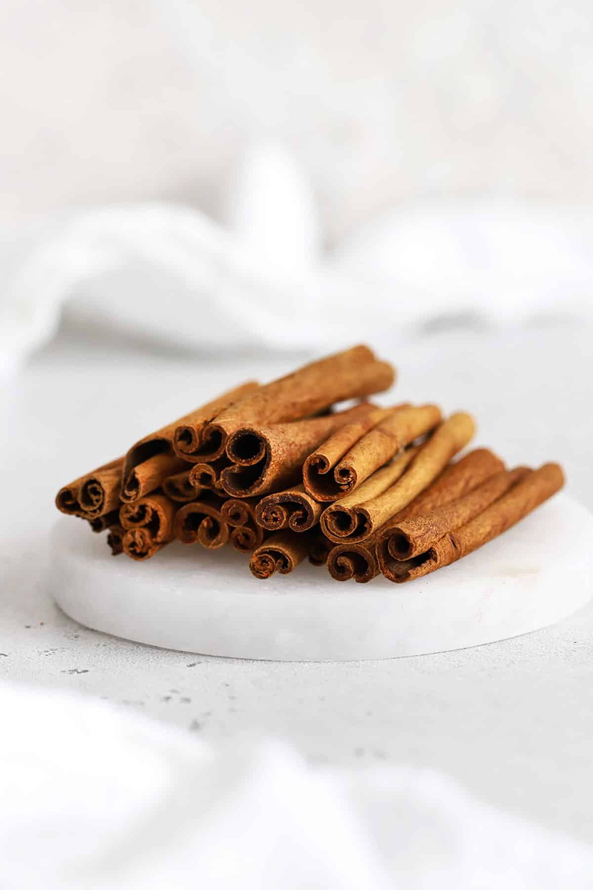 Front view of a stack of cinnamon sticks on a white coaster