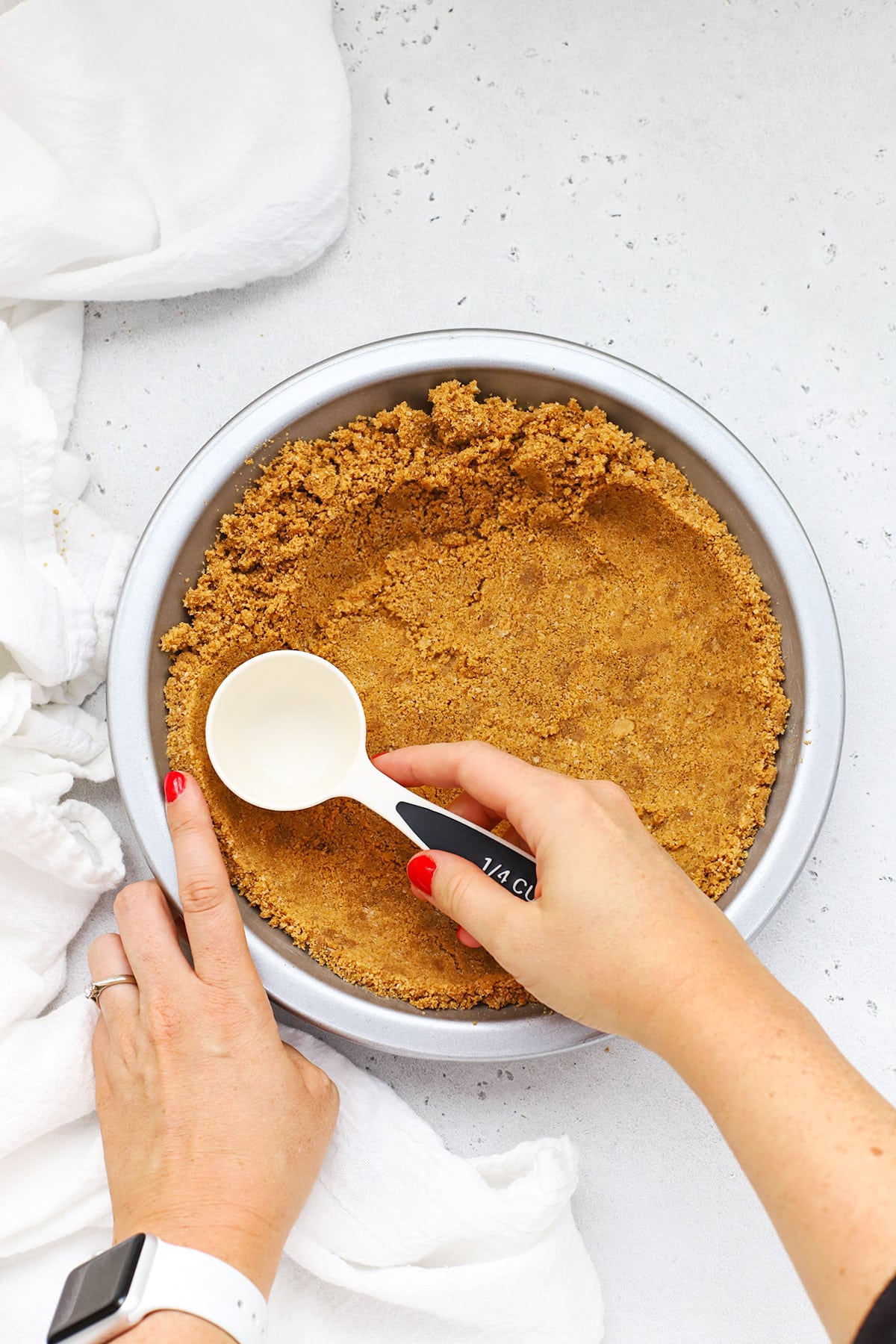 Patting out a gluten-free graham cracker crust into a metal pie pan