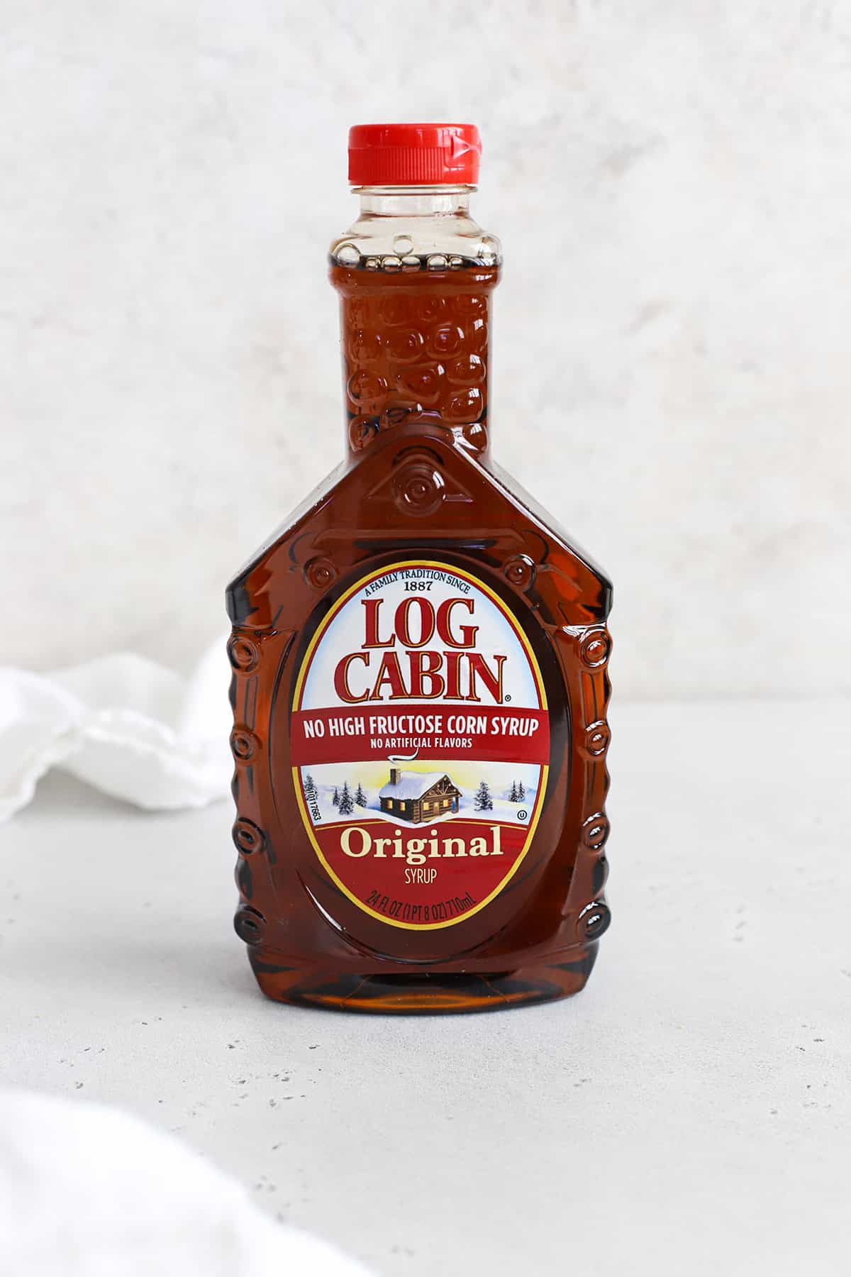 Front view of a bottle of log cabin pancake syrup on a white background