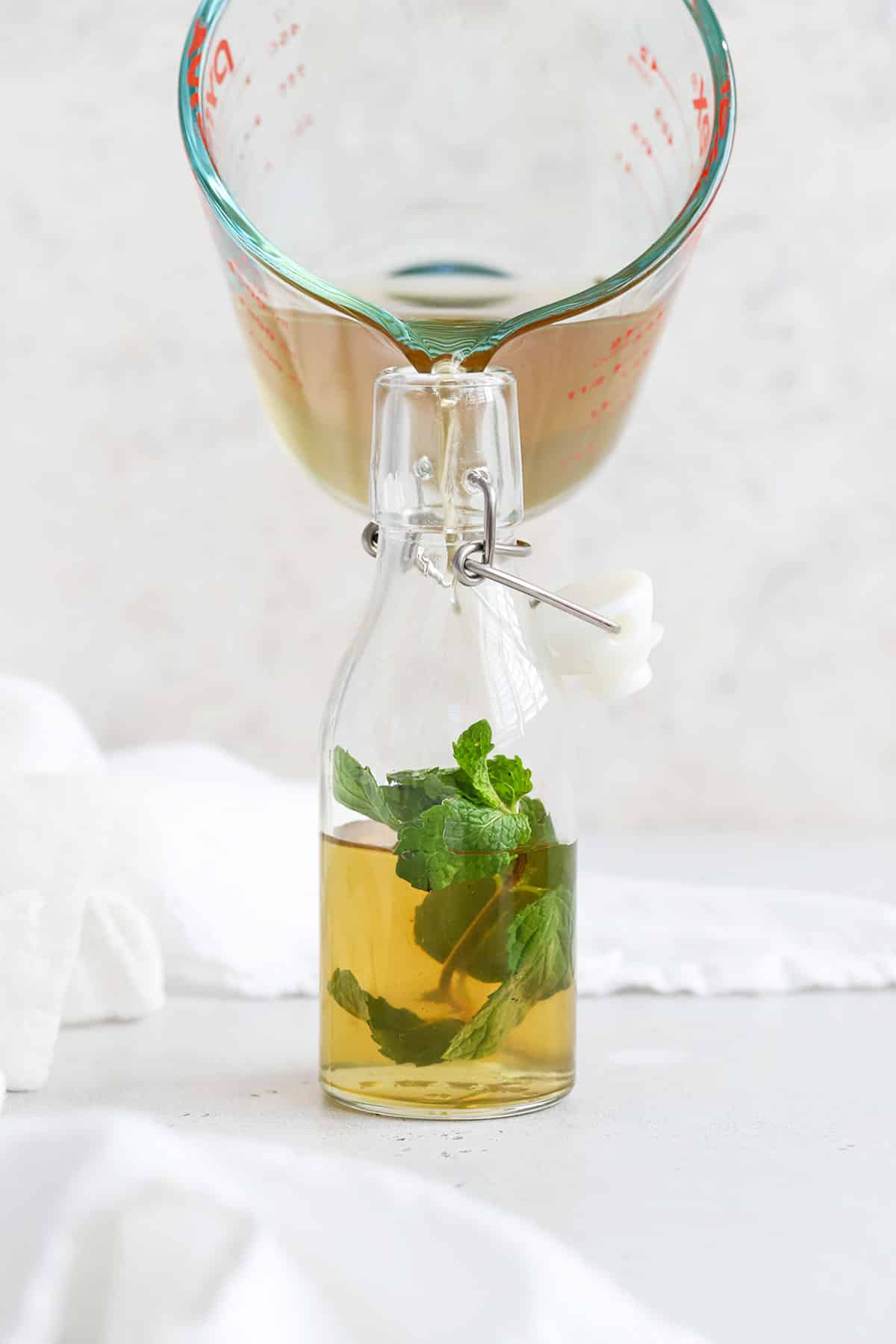 Pouring mint simple syrup into a jar