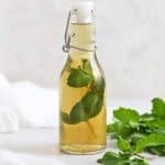 Front view of a jar of mint simple syrup with mint leaves