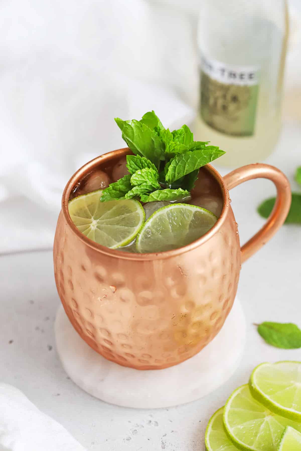 Front view of a non-alcoholic moscow mule mocktail in a copper mug with fresh mint and lime slices