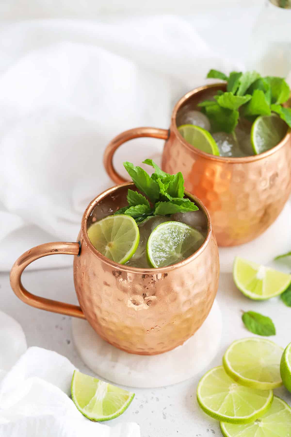 Front view of two non-alcoholic moscow mule mocktails in copper mugs with fresh mint and lime slices