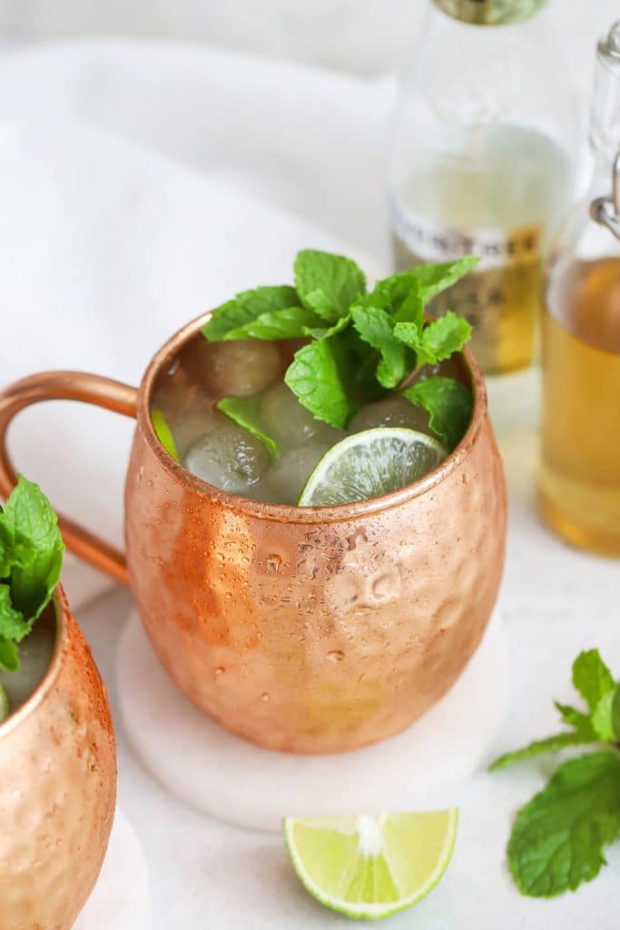 Front view of two non-alcoholic moscow mule mocktails in copper mugs with fresh mint and lime slices