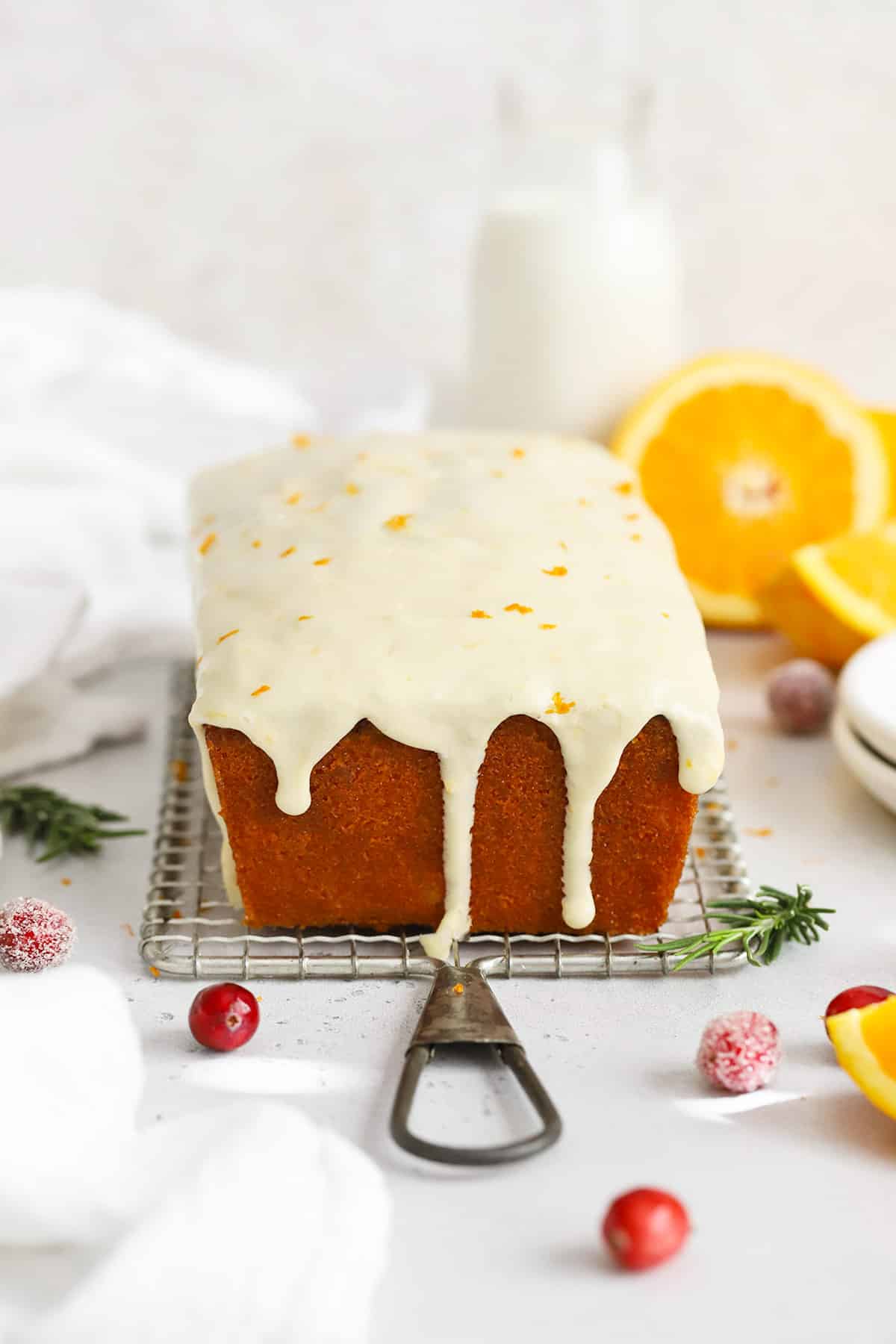 Front view of gluten-free cranberry orange loaf cake with orange glaze dripping down the sides