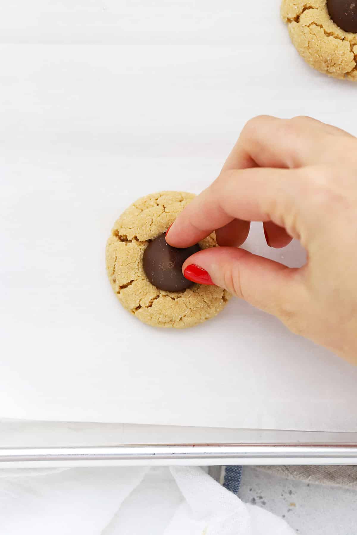 adding a Hershey's kiss to the center of a small peanut butter cookie to make gluten-free peanut butter blossom cookies
