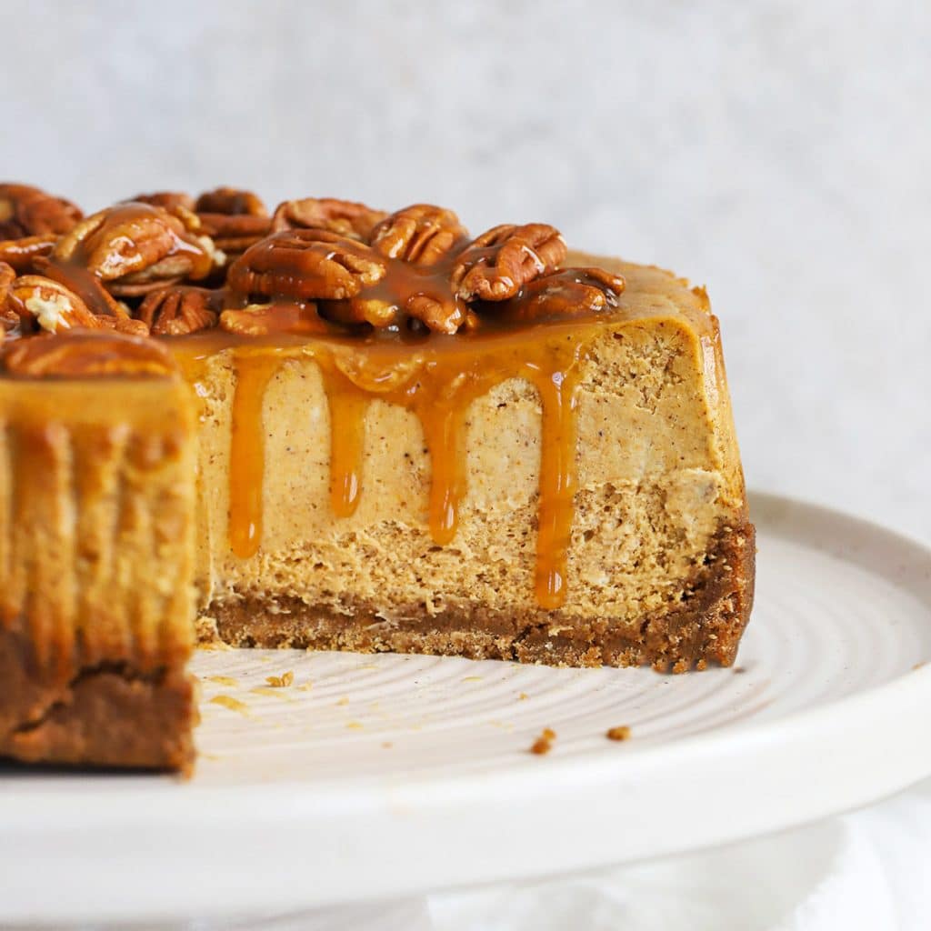 Front view of a gluten-free pumpkin cheesecake topped with caramel and pecans