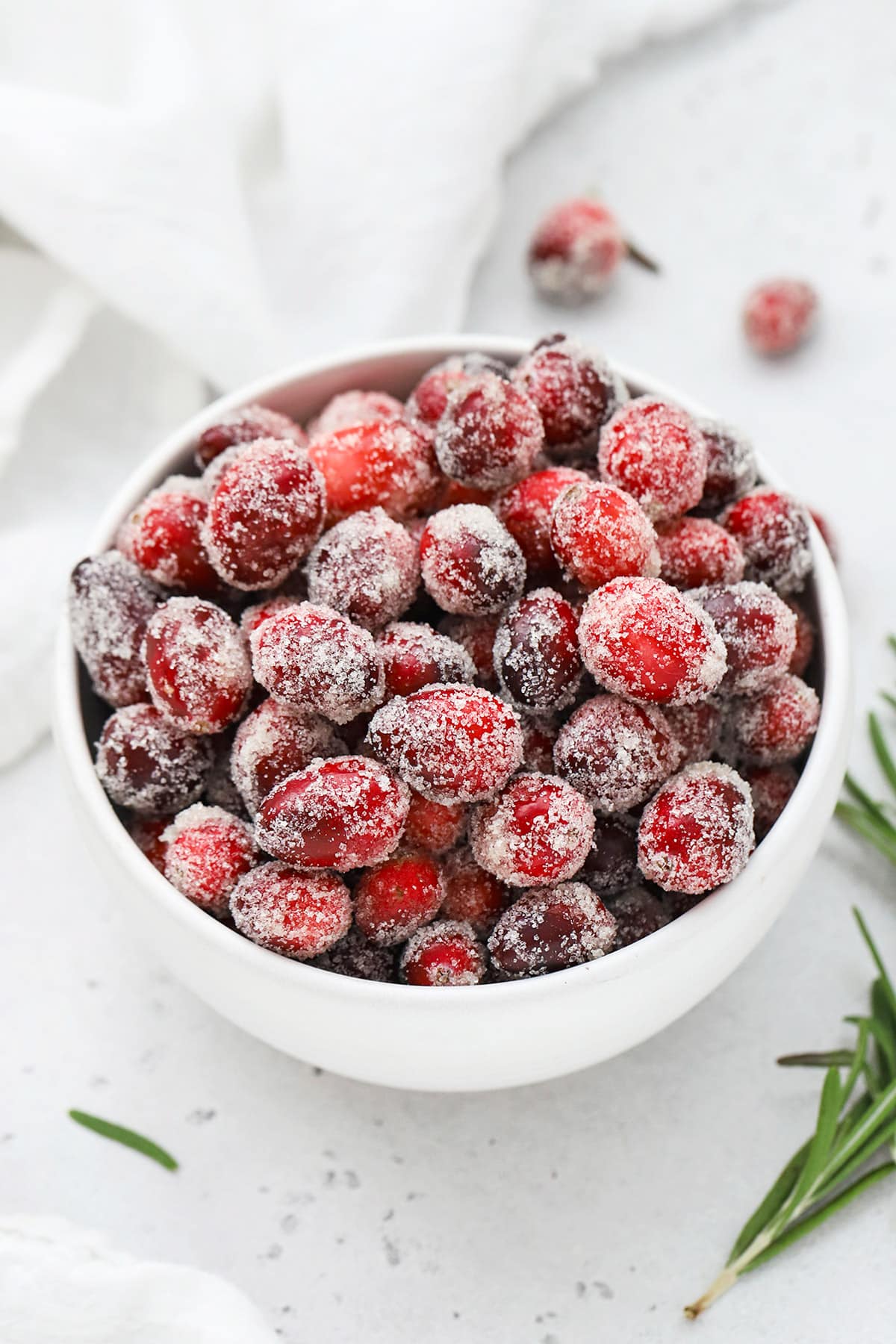 Front view of a white bowl of candied cranberries covered with sugar