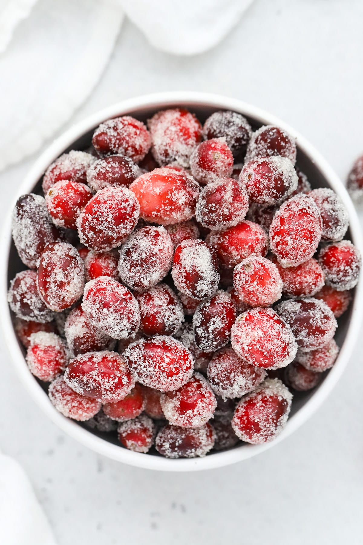 Overhead view of a white bowl of candied cranberries covered with sugar