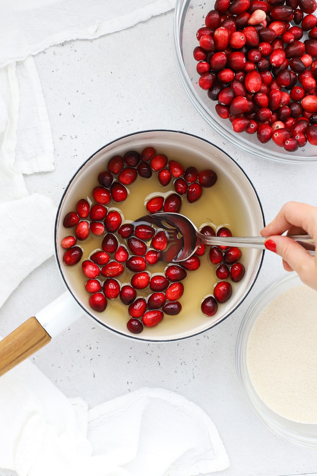 Dipping fresh cranberries in simple syrup to make sugared cranberries