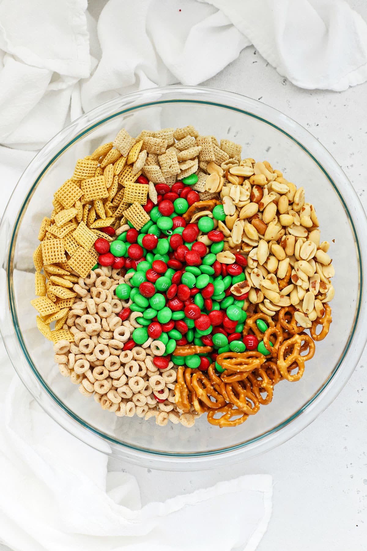 Ingredients for gluten-free Christmas chex mix in a large glass bowl