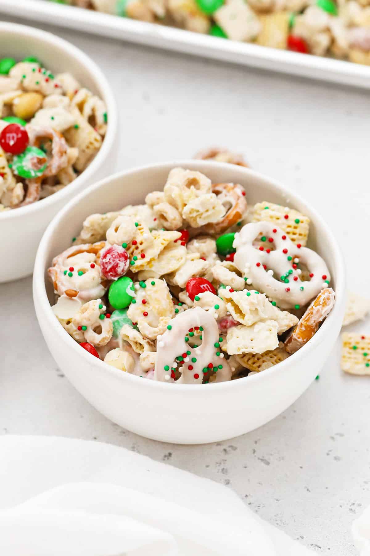 Large white bowl of gluten-free holiday chex mix with m&ms and pretzels