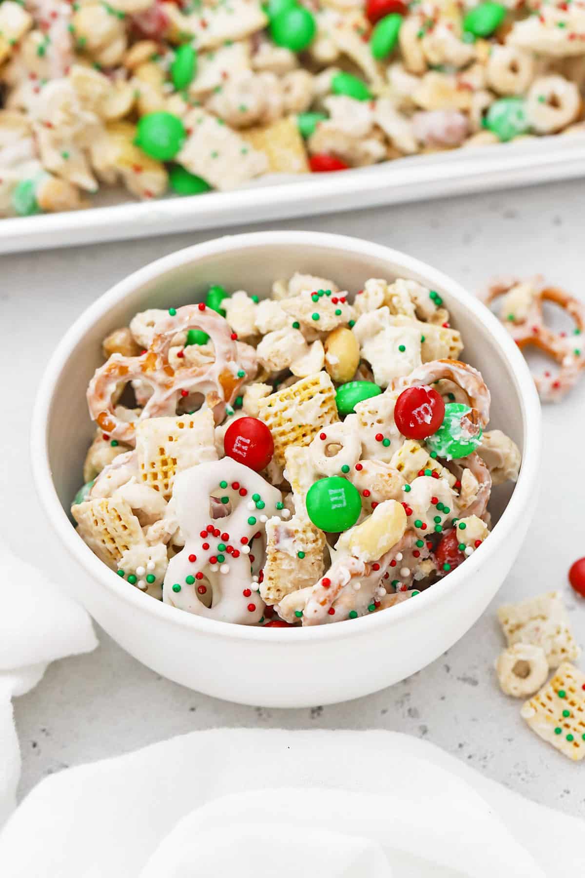 Large white bowl of gluten-free holiday chex mix with m&ms and pretzels