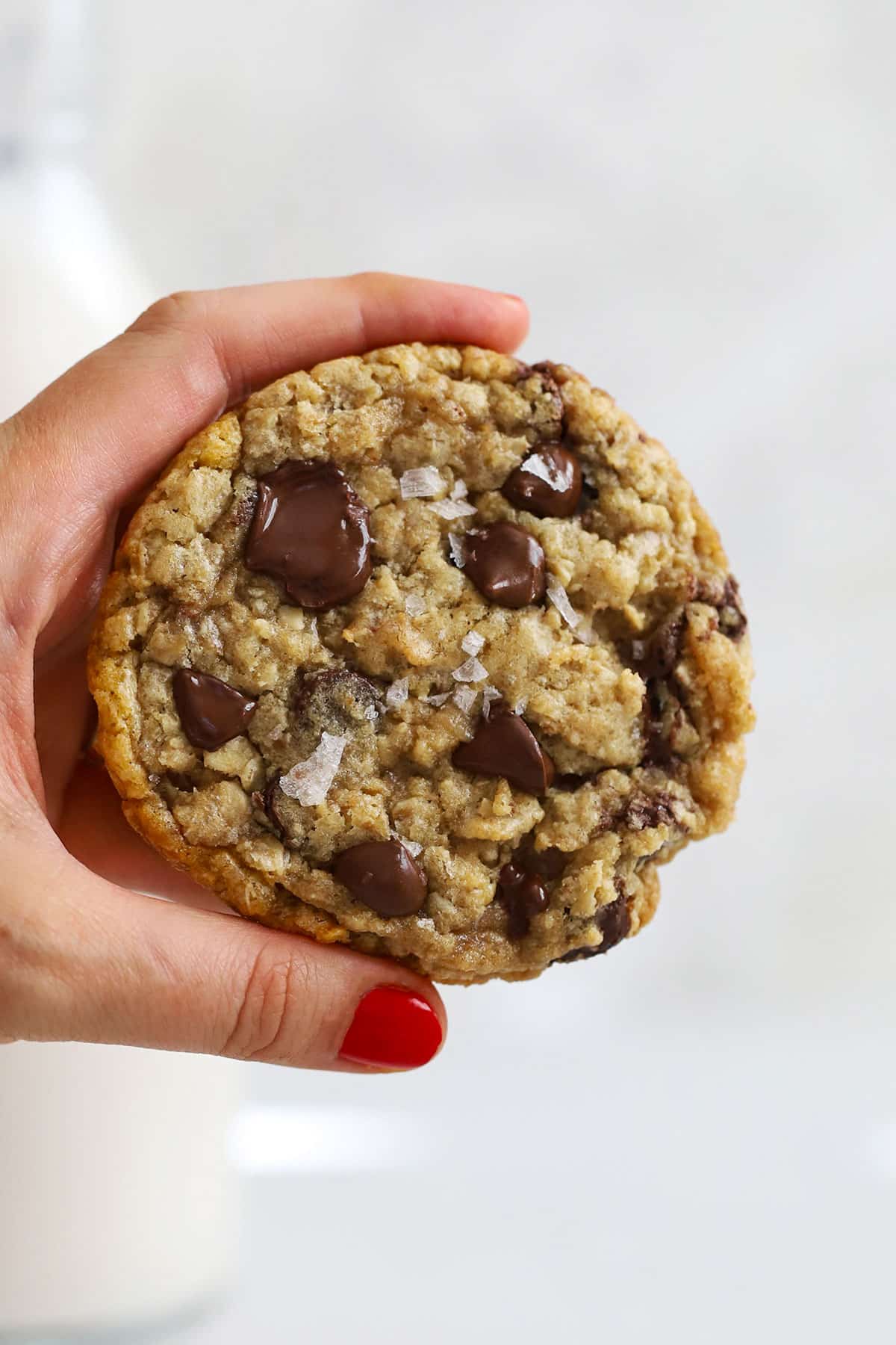 Hand holding a soft, chewy gluten-free oatmeal chocolate chip cookie