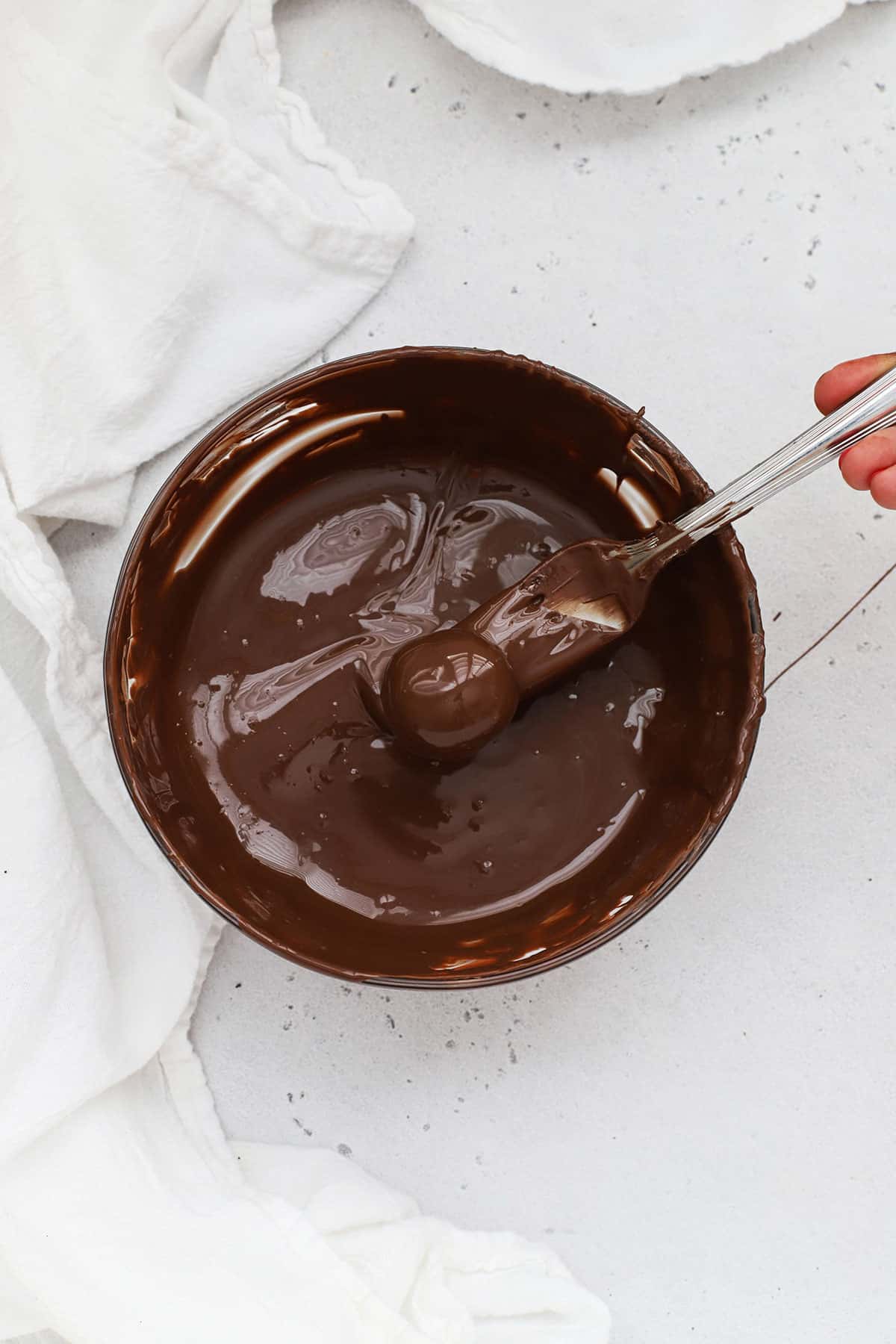 Dipping gluten-free Oreo balls into melted chocolate