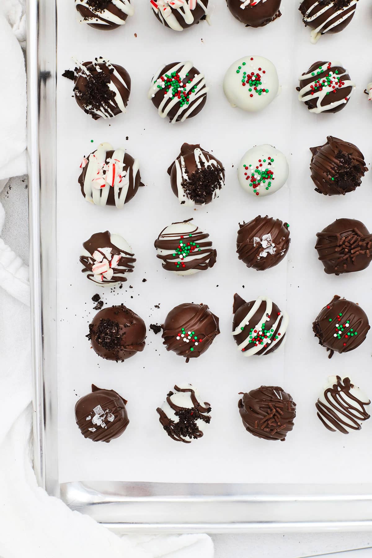 Gluten-free Oreo truffles setting on a baking sheet, topped with different toppings