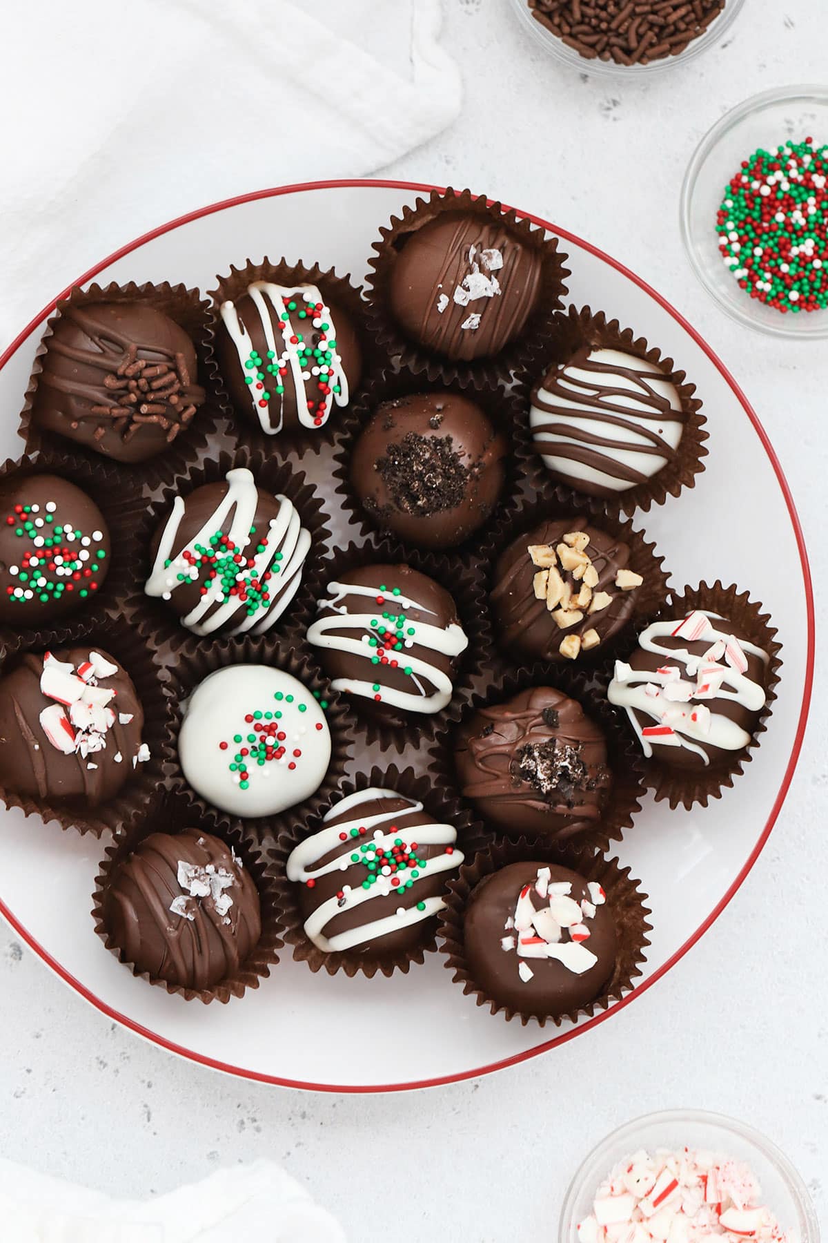 Gluten-free Oreo truffles decorated with different toppings on a white plate with a red rim
