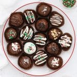 Gluten-free Oreo truffles decorated with different toppings on a white plate with a red rim